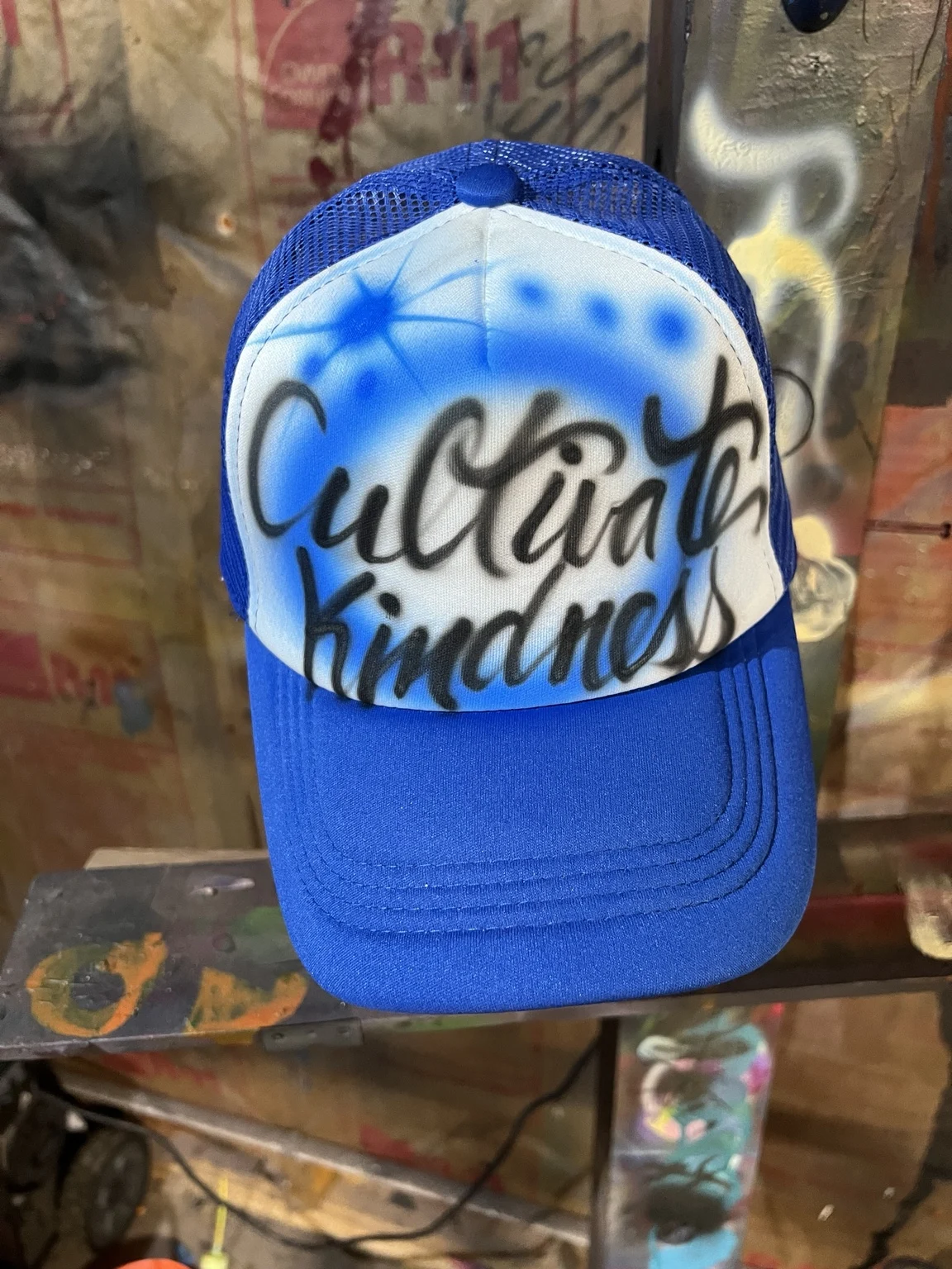 Blue trucker hat with black script lettering and blue airbrush star details for 7 Brew in Nashville