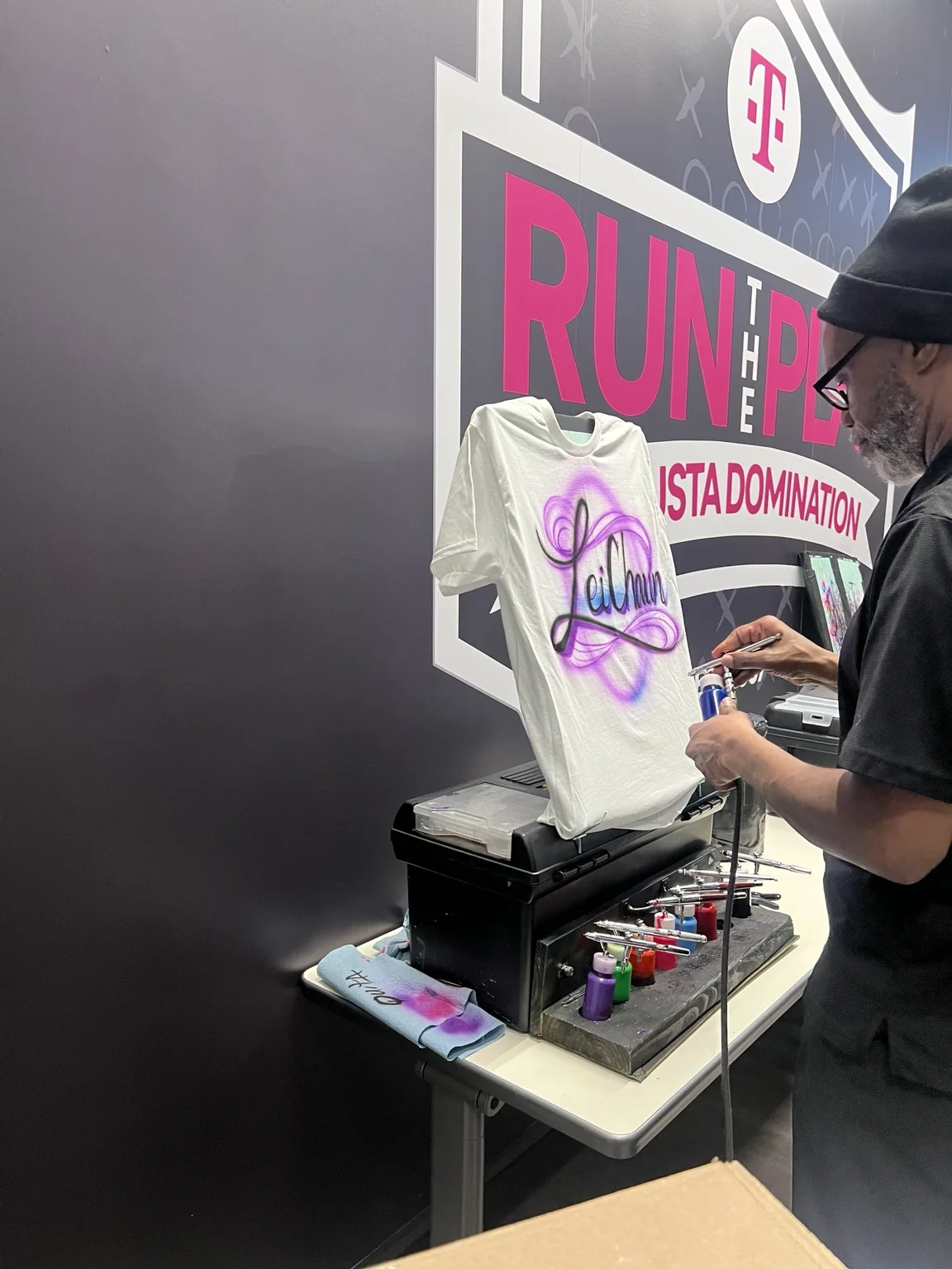 On-site airbrush artist customizing a shirt at the Augusta T-Mobile event