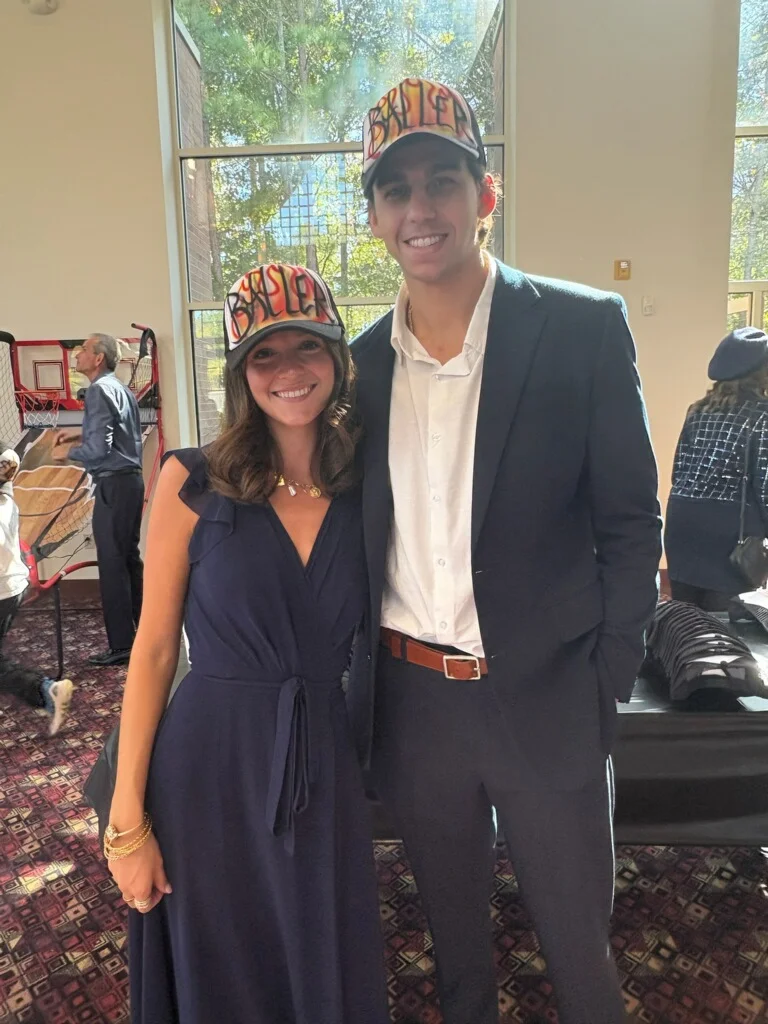 Two guests wearing custom airbrushed trucker hats at a corporate gathering in Monroe